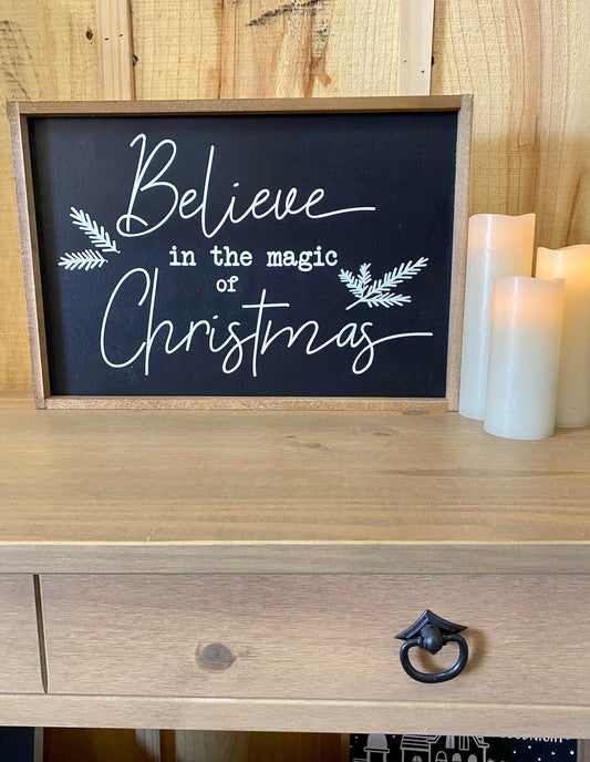 Believe in the magic of christmas black background mistletoe wood sign